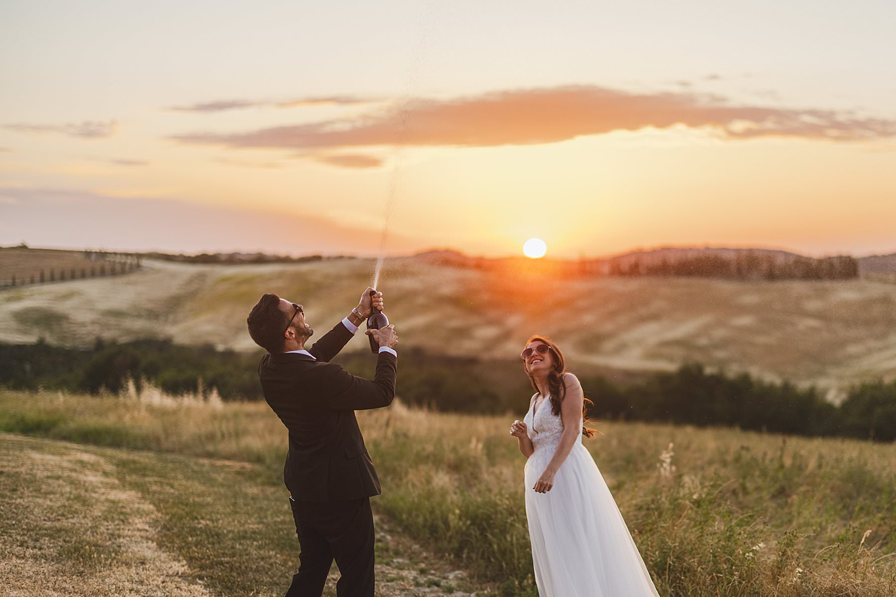 Exciting bride and groom elopement celebration in the golden hour light in the countryside of Tuscany at Vitaleta Chapel near Pienza