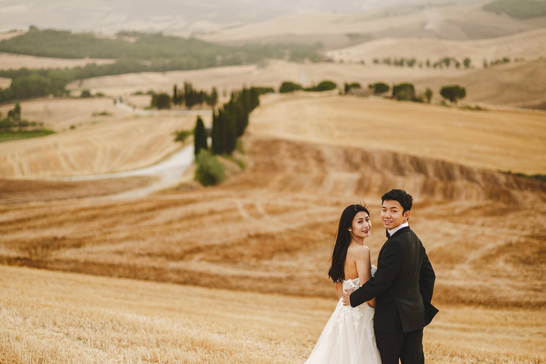 Romantic couple dressed with wedding dresses engagement pictures in iconic and dreaming countryside of picturesque village of Pienza heart of Tuscany